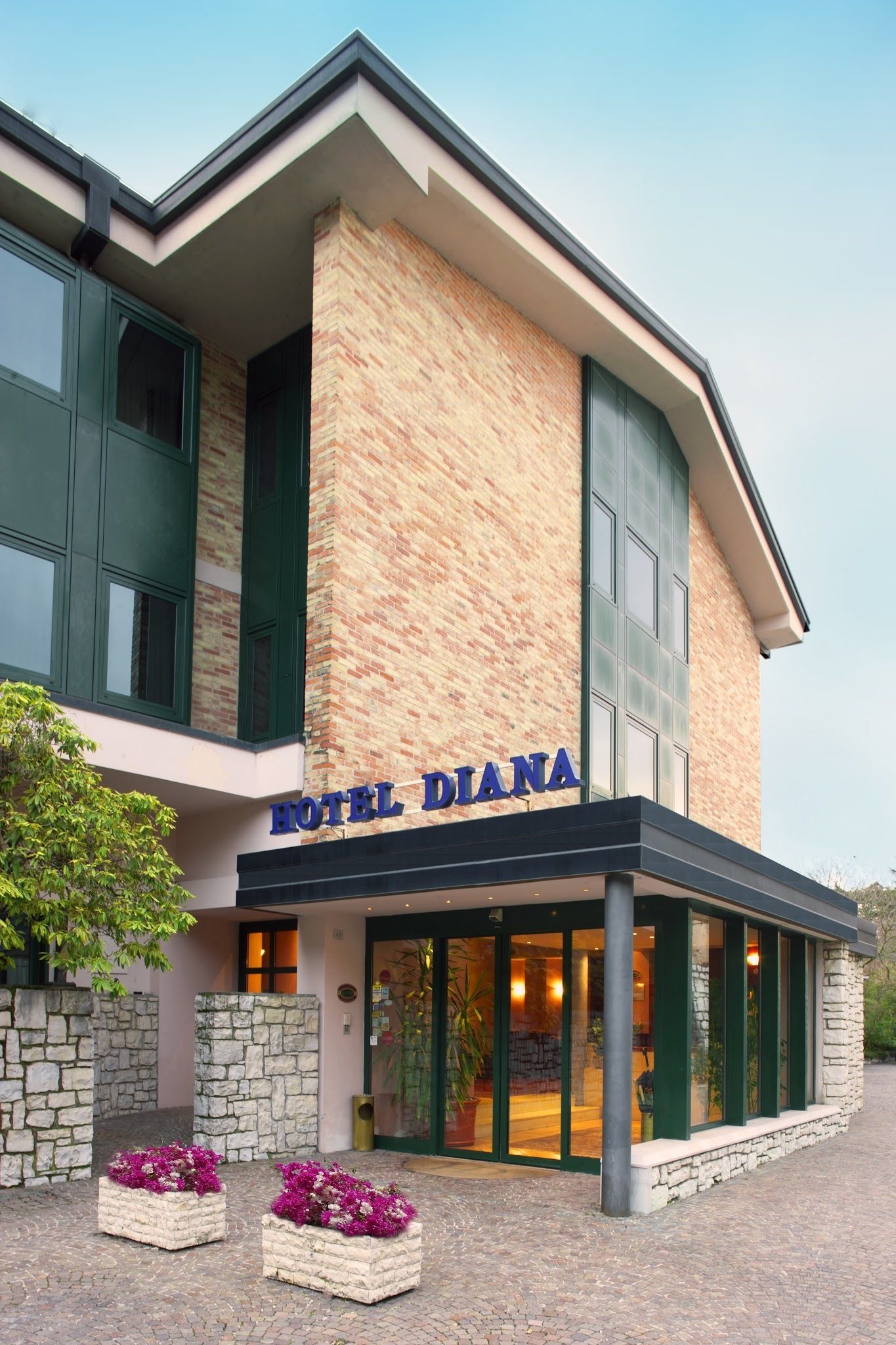 A hotel named "HOTEL DIANA" with a brick facade, large windows, and a stone entrance.