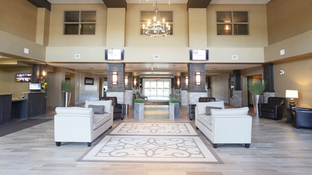A spacious lobby with a chandelier, two sofas, a reception desk, and a large window.