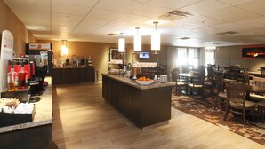 A hotel lobby with a central island, a coffee station, and a seating area with tables and chairs.