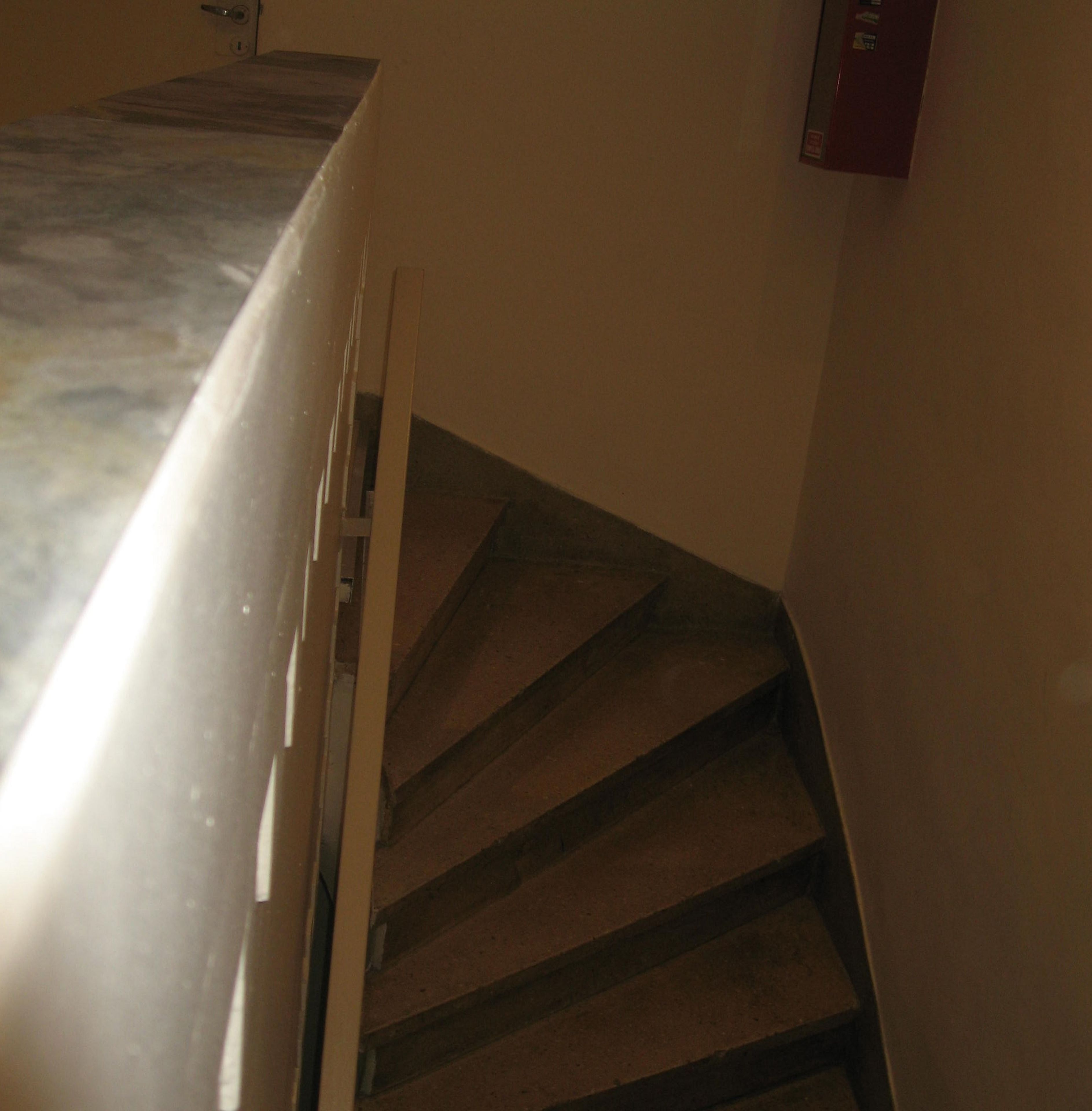 A staircase with a handrail and a light source to the left.