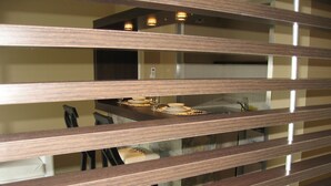 Vista a través de persianas, se aprecia un comedor con una mesa y vajilla.