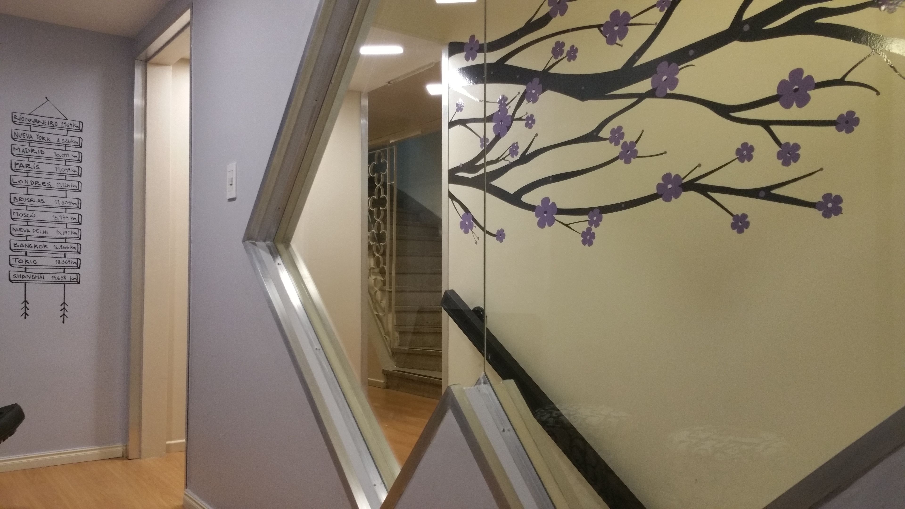 Un corridoio con una cartina a parete e un albero ornamentale con fiori viola.