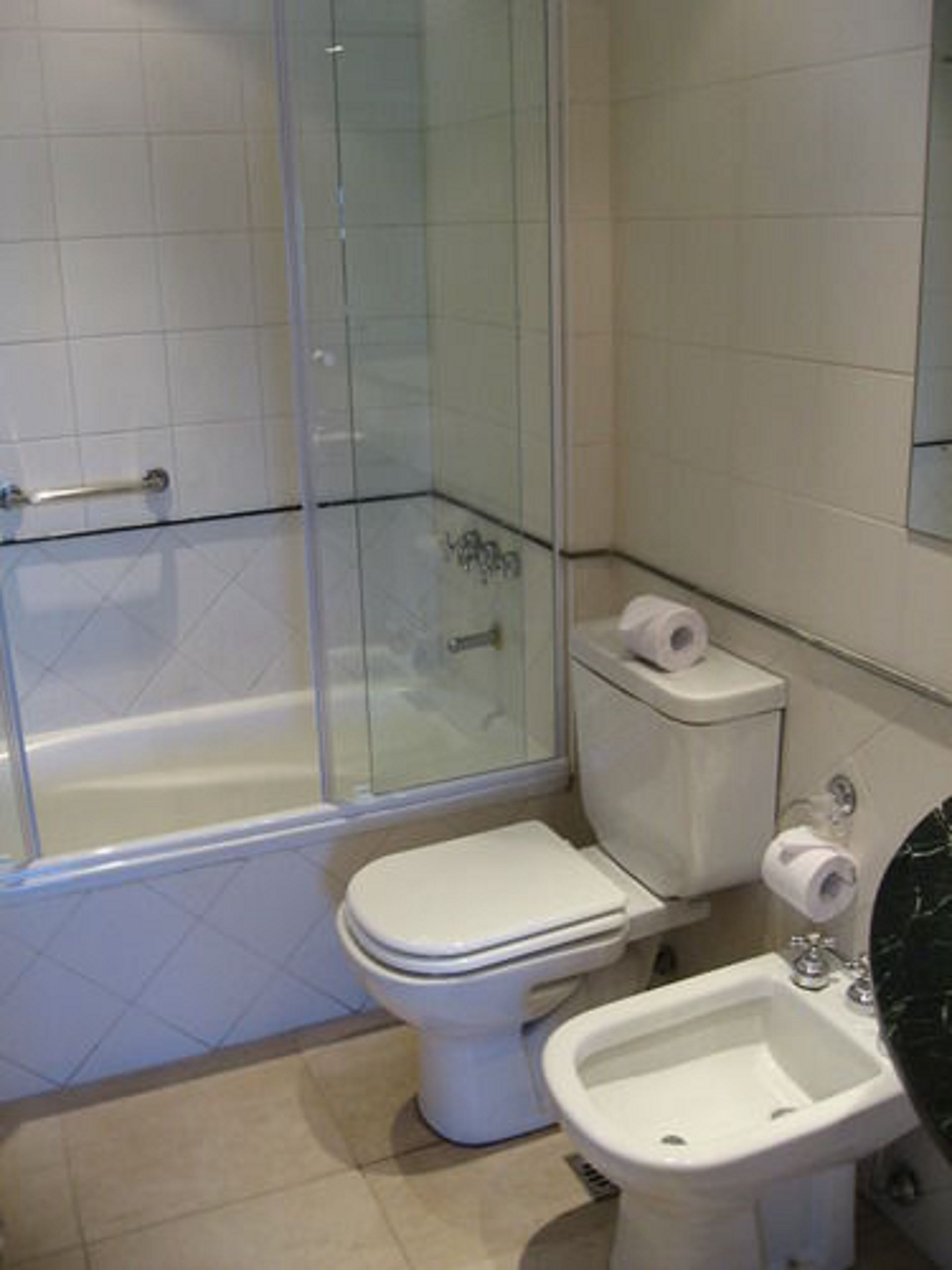 A bathroom with a glass-enclosed shower, a toilet, and a bidet.
