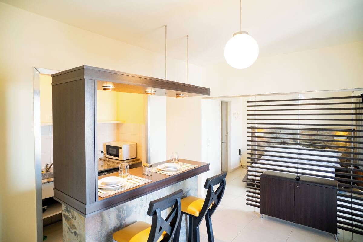 A modern kitchen with a central island, bar stools, and a built-in microwave.