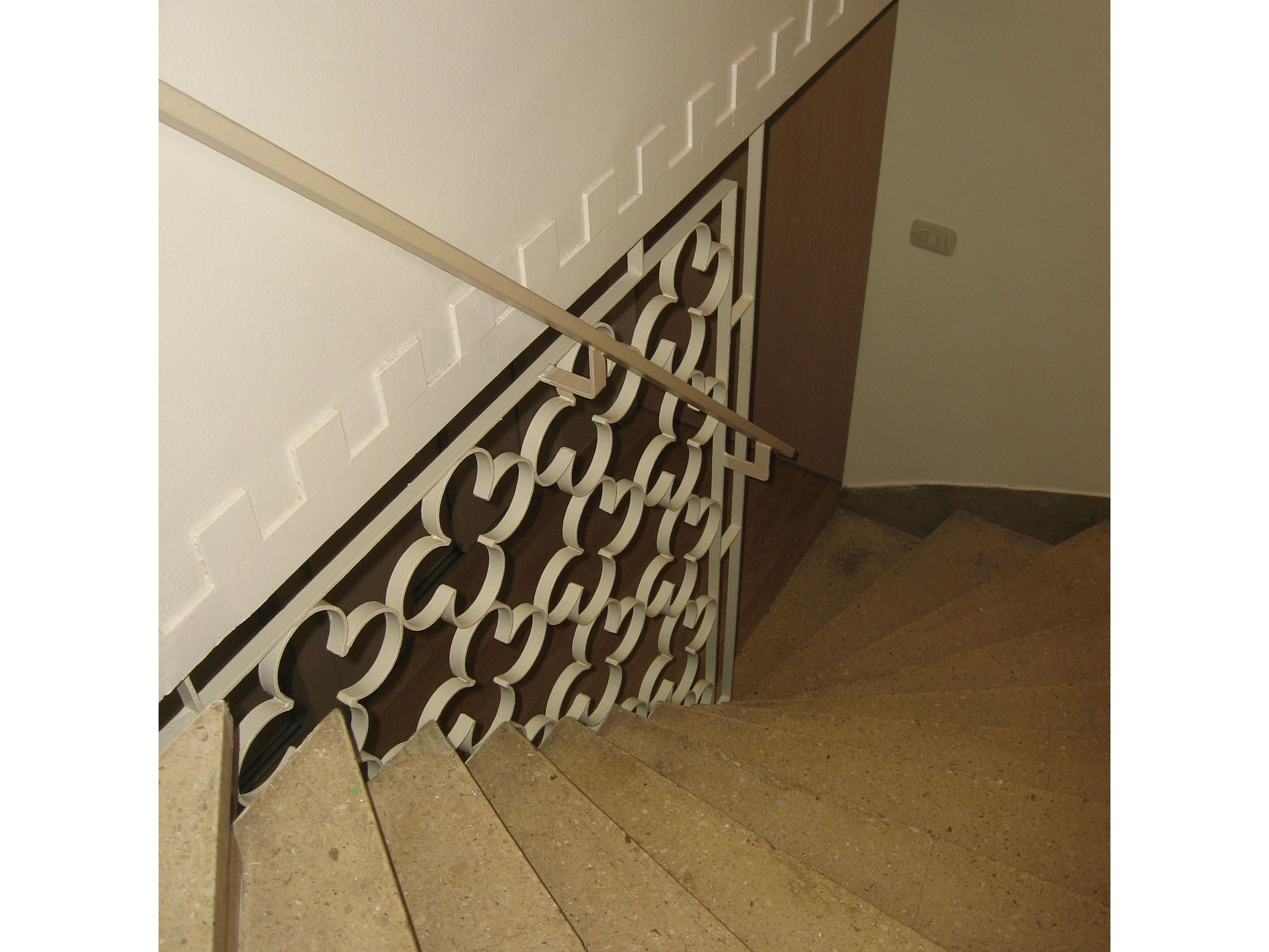 A staircase with a decorative metal railing and a wooden handrail.