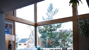 A cozy living room with a large window, a sofa, a coffee table, and a plant. - Hosteria Foike (Ushuaia)