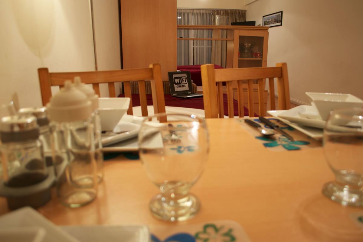 Una mesa de comedor dispuesta con sillas, una computadora portátil y un cartel de Wi-Fi.