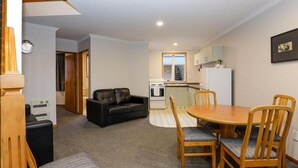 A compact living space with a dining area, kitchen, and a staircase leading to an upper level. - ASURE Chelsea Gateway Motor Lodge (Westport)