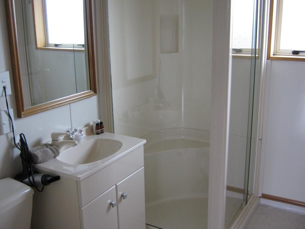 Un baño con lavamanos blanco, espejo y cabina de ducha de vidrio.