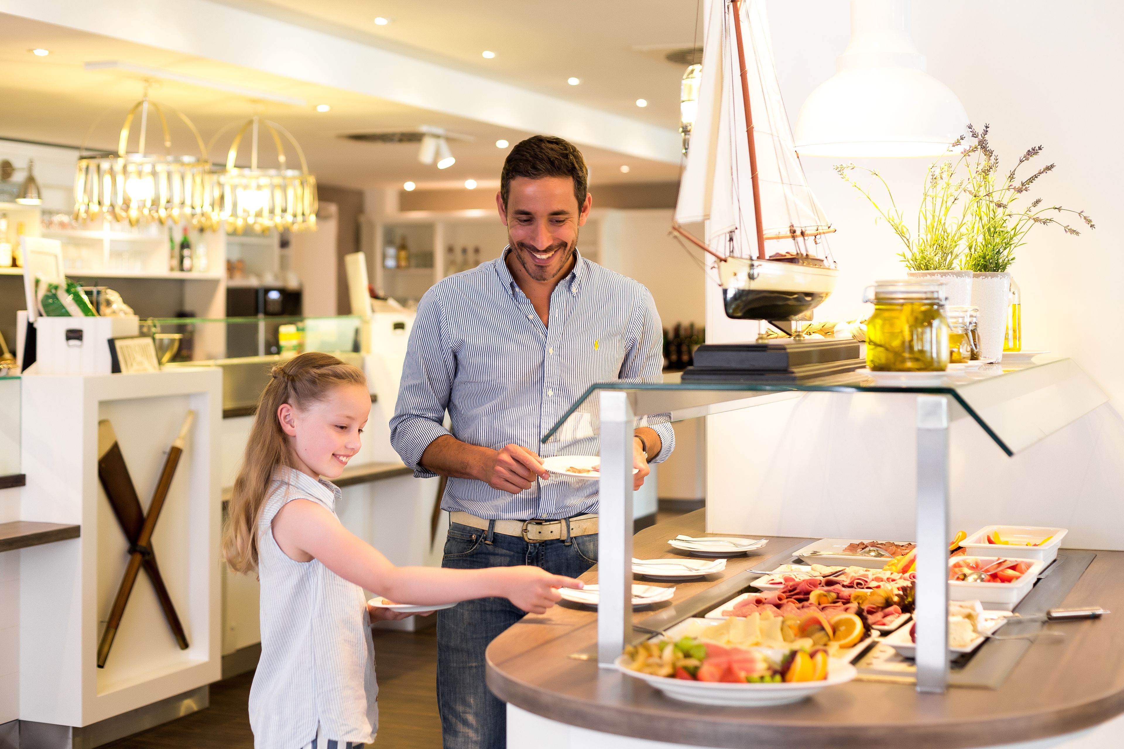 Ein Buffet mit verschiedenen Speisen und einer Segelboot-Dekoration im Hintergrund.