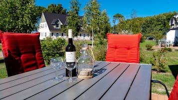 A table with a bottle of wine, two glasses, and a glass jar with a rope handle.