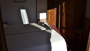 A bedroom with two beds, a wooden wardrobe, and a framed picture on the wall. - Piccolo Chalet (Sauze d'Oulx)
