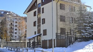 A multi-story building with a flat roof, a balcony, and a wooden fence. - Piccolo Chalet (Sauze d'Oulx)