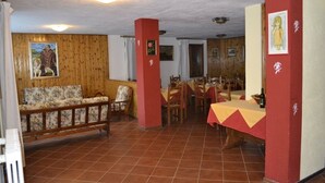 A dining area with wooden walls, a sofa, and a table set for dining. - Piccolo Chalet (Sauze d'Oulx)