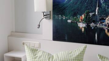 Ein Hotelzimmer mit Bett, Nachttisch, Lampe und einer großen Wandmalerei mit Landschaftsmotiv.