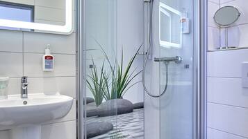 Un baño moderno con ducha de vidrio, lavamanos e inodoro.