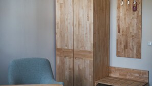 Una habitación con un armario de madera, un banco y un perchero con ganchos.