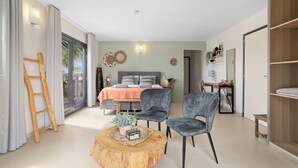 Un dormitorio moderno con una cama, dos sillas, una mesa redonda de madera y un armario.