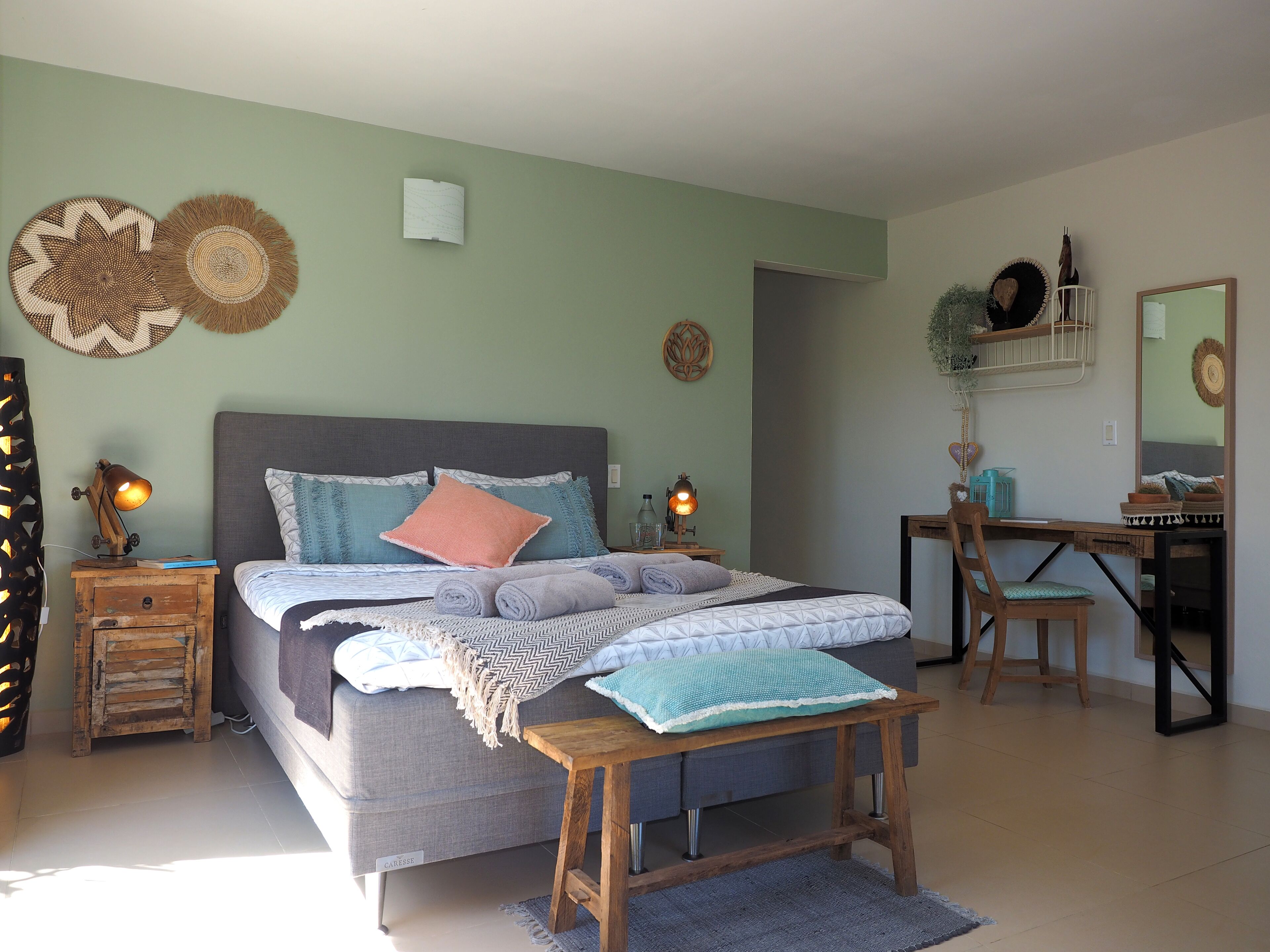 A bedroom with a bed, bedside tables, a desk, and a chair.