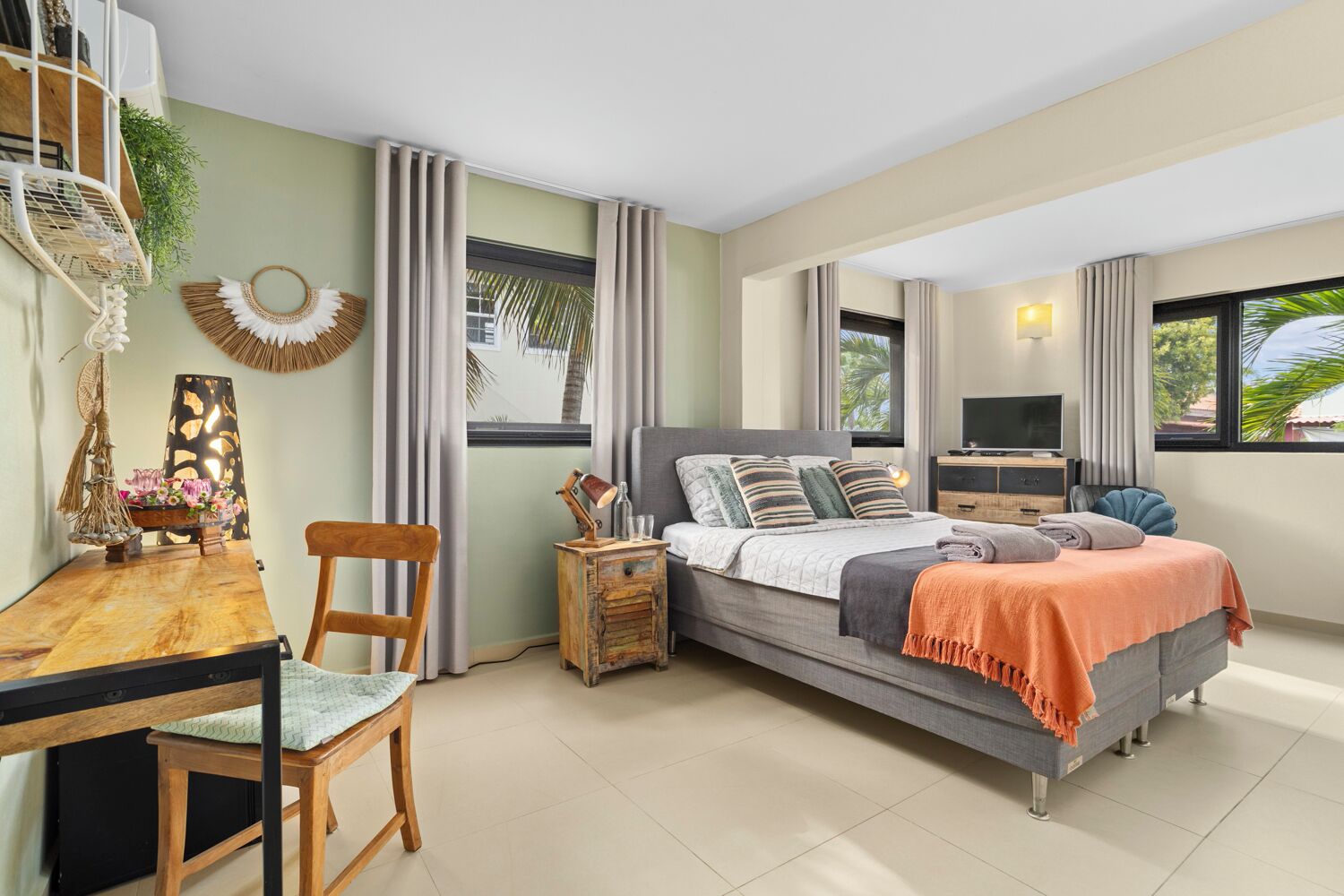 A bedroom with a bed, bedside table, TV, and a desk with chair.