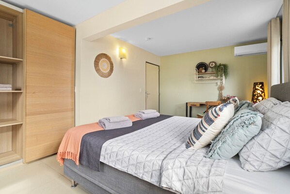 Un dormitorio con cama, armario, estante en la pared y una puerta.