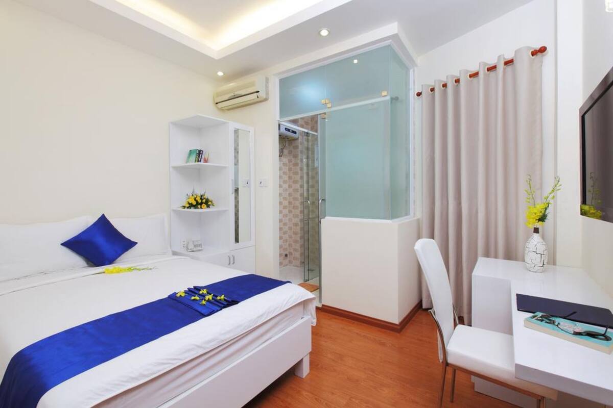 Ein modernes Hotelzimmer mit Bett, Schreibtisch, Stuhl, Kleiderschrank und Duschbereich.