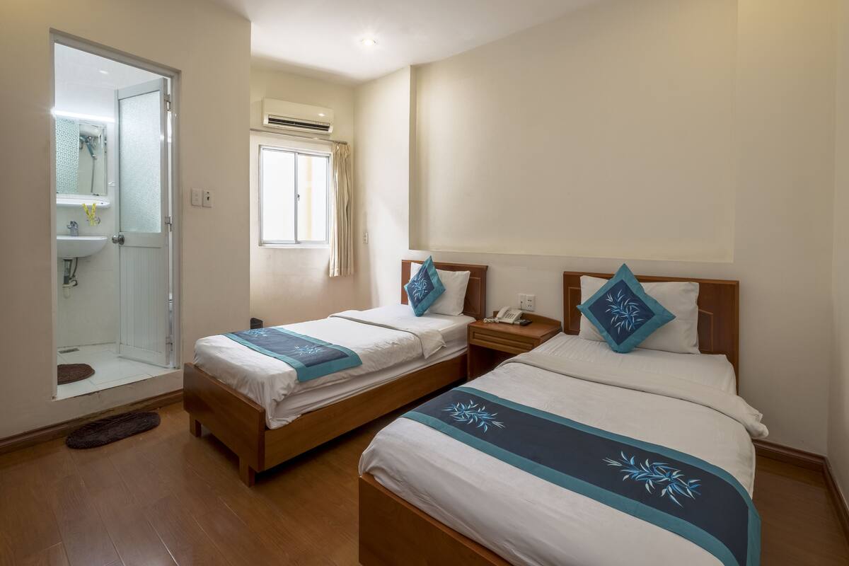 Ein Hotelzimmer mit zwei Betten, einem Badezimmer und einem Fenster mit Vorhängen.