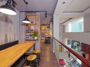 A modern interior with a wooden dining table, bar stools, and a bookshelf.