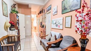 A hallway with a sofa, chairs, a vase with flowers, and various wall decorations. - Lavender Lodge (Kota Kinabalu)