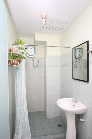 A bathroom with a white sink, a shower, and a mirror. There is a plant in a basket on the wall. - Lavender Lodge (Kota Kinabalu)