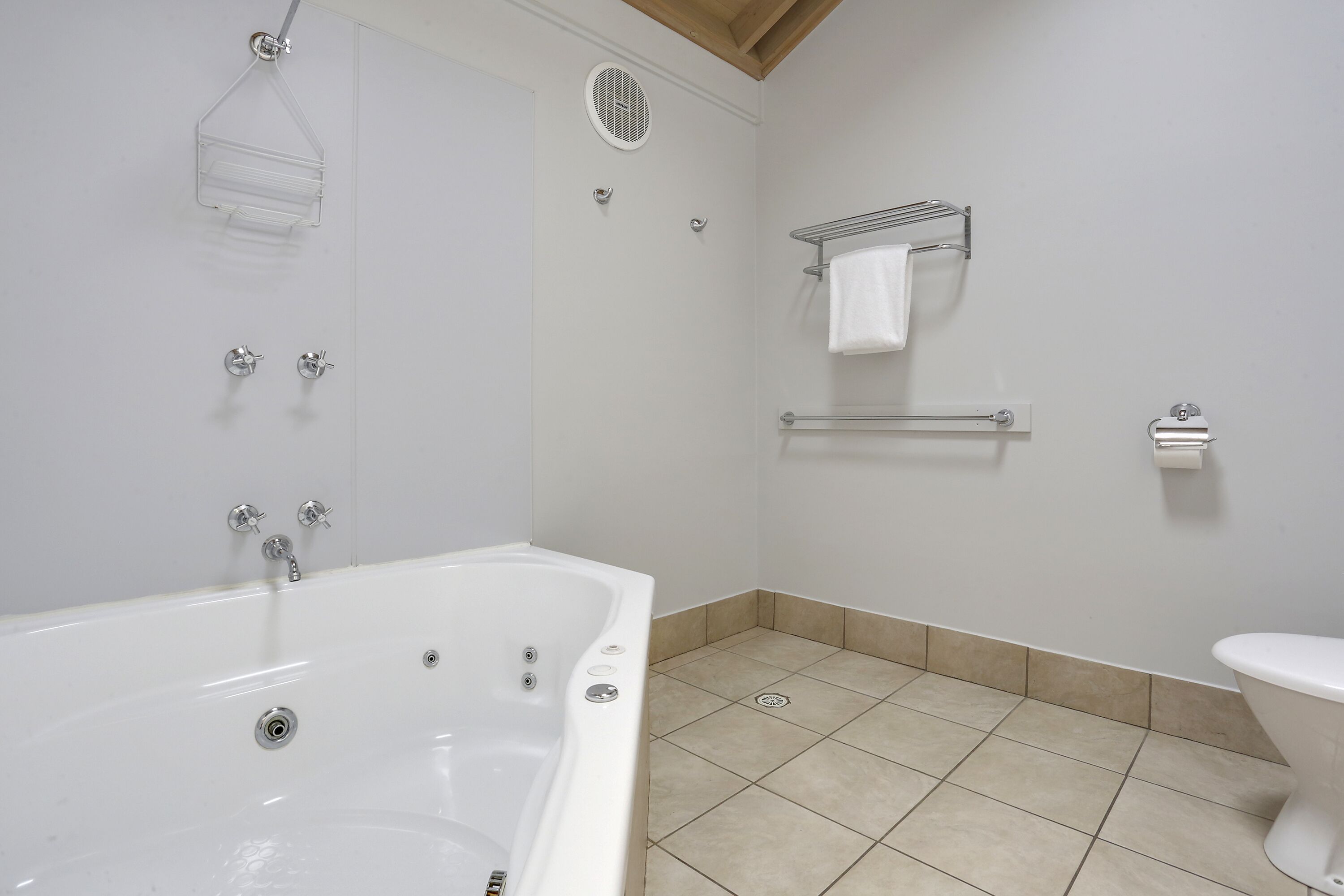 Un baño con bañera, ducha, inodoro y un perchero para toallas.