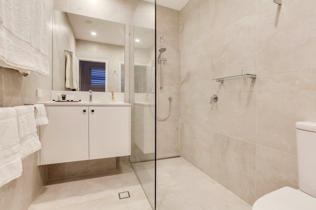 Une salle de bain moderne avec une douche à parois de verre, un lavabo blanc et des toilettes.