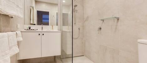 Ein modernes Badezimmer mit einer Duschkabine, einem weißen Waschbecken und einer Toilette.