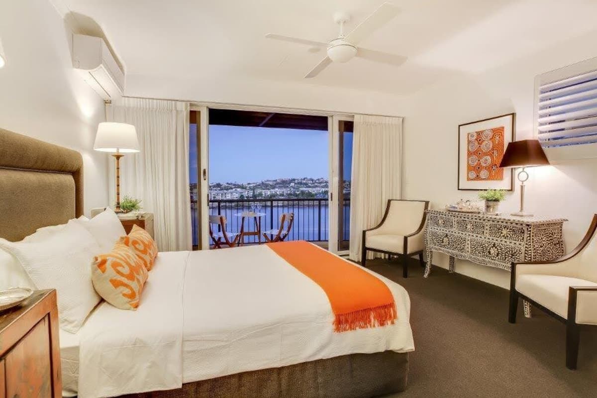 Une chambre d’hôtel équipée d’un lit, d’un bureau, de chaises, d’un balcon avec vue et d’un ventilateur de plafond.