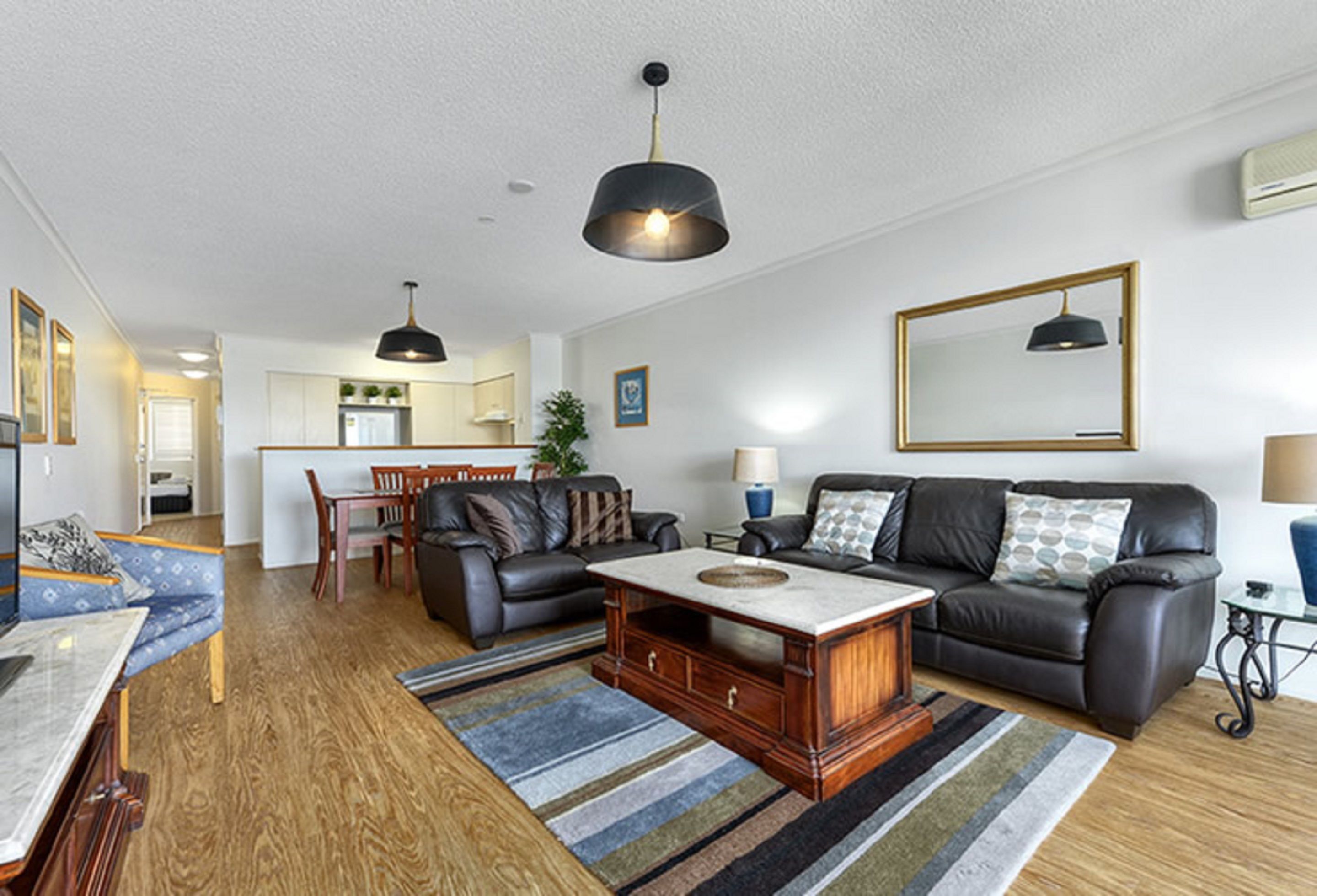 A modern living room with a sofa, coffee table, and dining area.