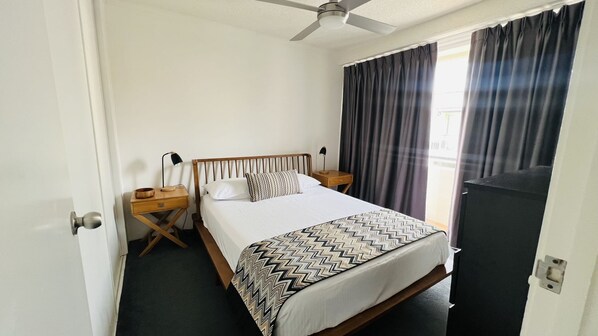 Une chambre d’hôtel avec un lit, deux tables de chevet, un ventilateur de plafond et un téléviseur.