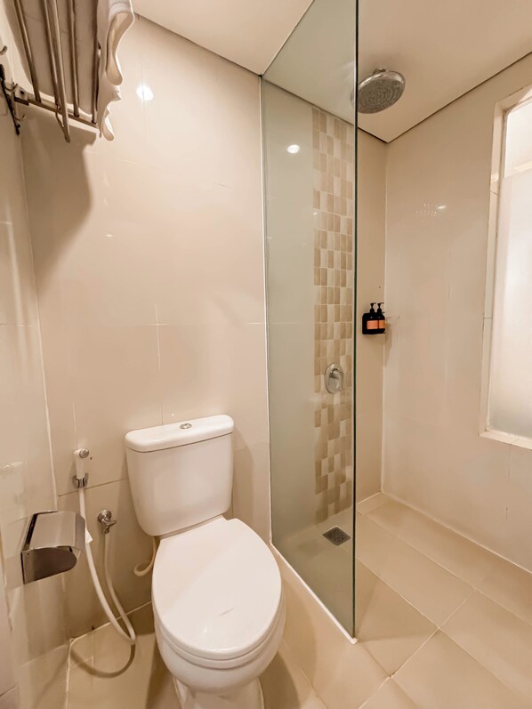 A bathroom with a toilet, a glass shower enclosure, and a tiled floor.