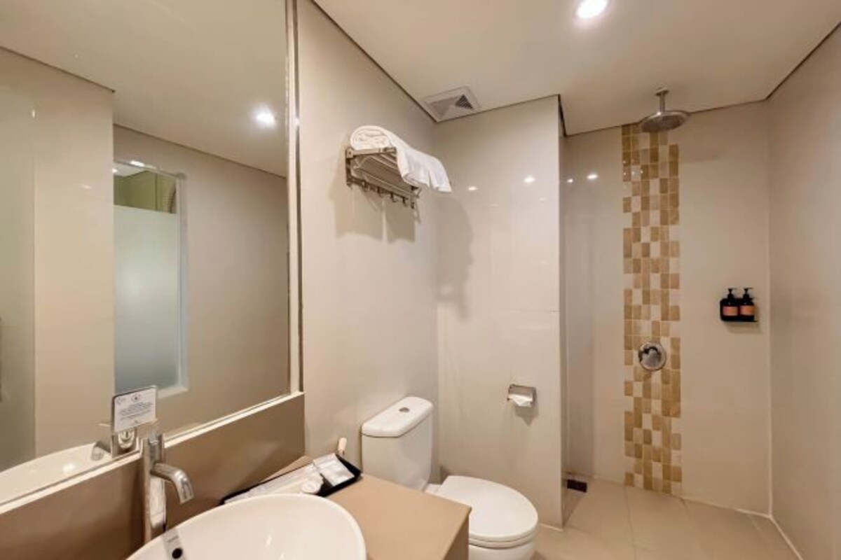 Un baño moderno con un espejo grande, un lavabo, un inodoro y una ducha.
