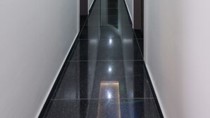 A modern, well-lit hallway with glossy black flooring and white walls. - Bürgerhofhotel Köln (Cologne)