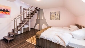 A bedroom with a bed, a wooden floor, a staircase, and a painting of the Eiffel Tower. - Bürgerhofhotel Köln (Cologne)