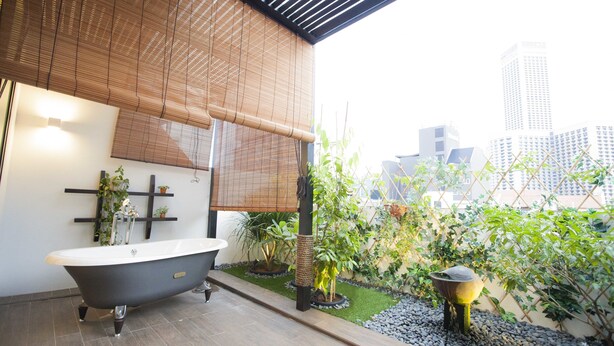 A modern bathroom with a freestanding bathtub, bamboo blinds, and a small garden area with plants and a water feature. - Hotel NuVe Heritage (Singapore)
