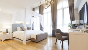 A modern bedroom with a four-poster bed, a desk with a chair, and a large window with curtains. - Hotel NuVe Heritage (Singapore)