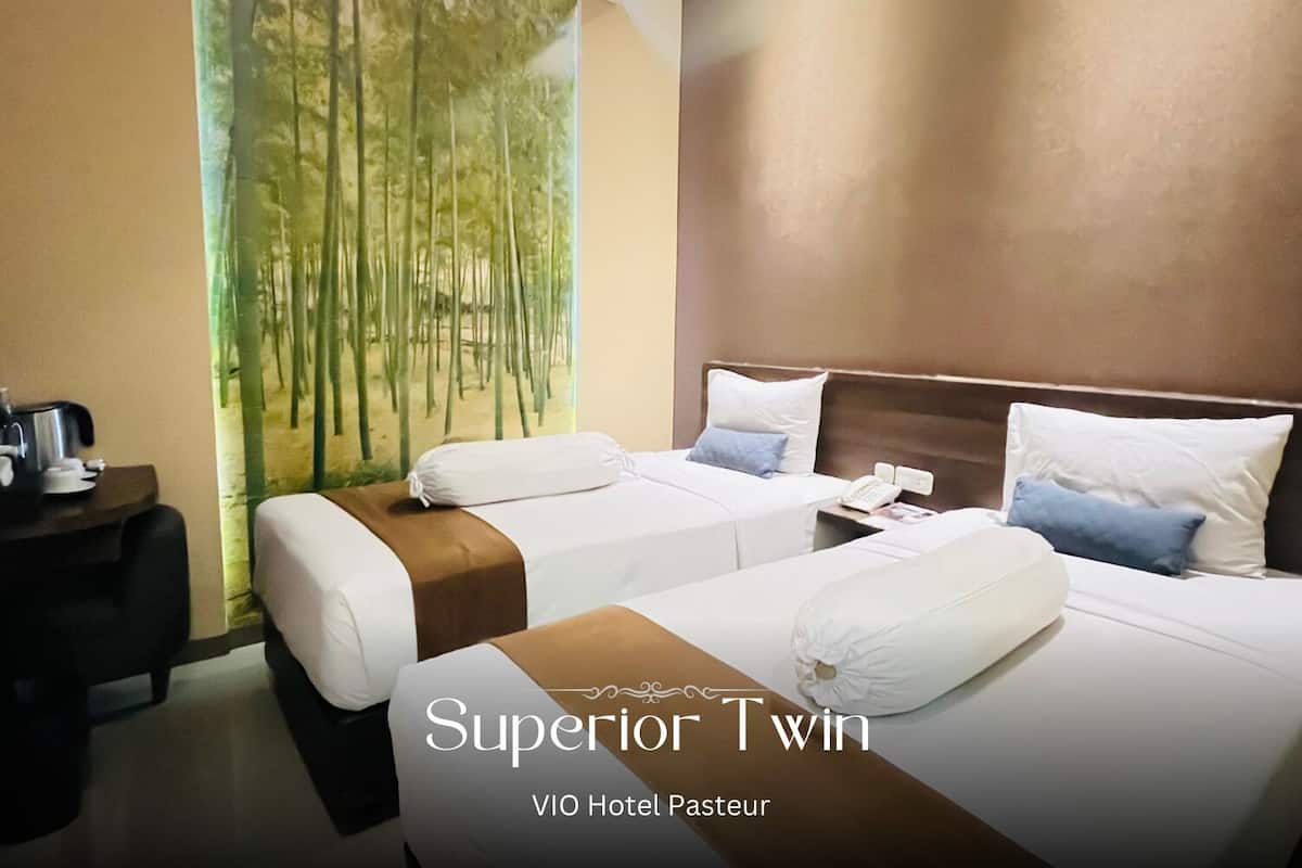 A hotel room with two beds, a nightstand, and a painting of bamboo.