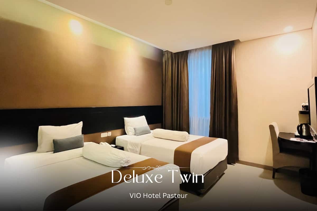 A Deluxe Twin room with two beds, a desk, and a chair.