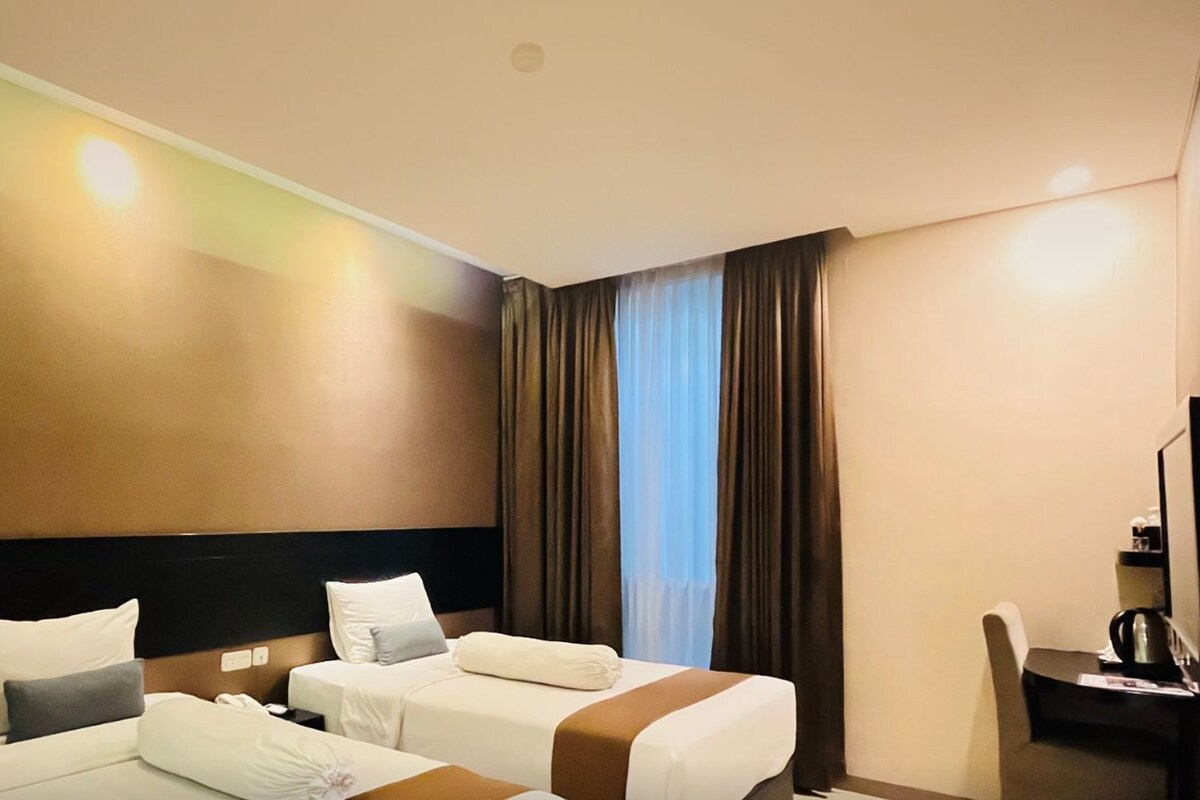 A Deluxe Twin room with two beds, a desk, and a chair.