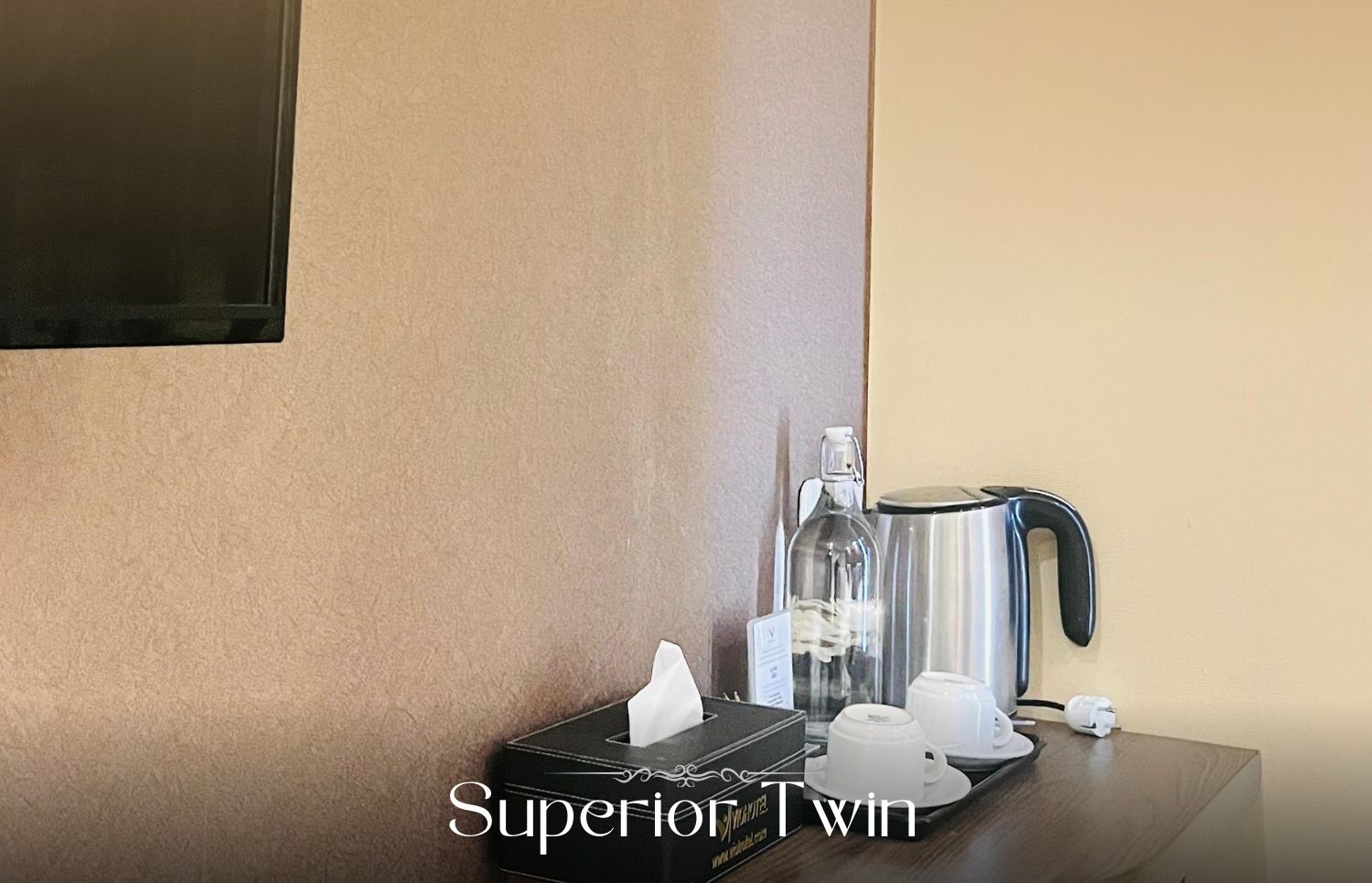 A hotel room with a minibar, a coffee maker, and a bottle of water on a wooden table.