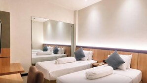 A hotel room with two single beds, a wooden headboard, a mirror, and a wooden nightstand. - Hotel Vio Cimanuk Bandung (Bandung)