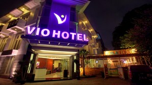 Ein Hotel mit einem gut sichtbaren 'VIO HOTEL'-Schild, einer Rezeption und einem sichtbaren Außenbereich mit Sitzgelegenheiten.