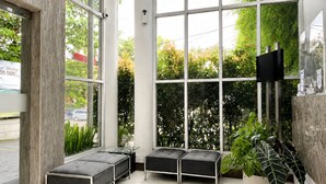 A modern interior with large windows, a flat-screen TV, and a seating area with cushioned benches. - Hotel Vio Express Surapati Bandung (Bandung)