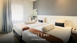 Une chambre d’hôtel avec deux lits, un grand miroir et une fenêtre avec des rideaux.